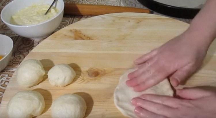 Pétrir chaque boule de pâte en un gâteau à plat avec les mains.