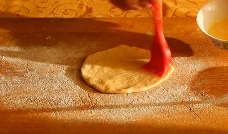 Roll a slice of dough into a cake and grease it with melted butter.