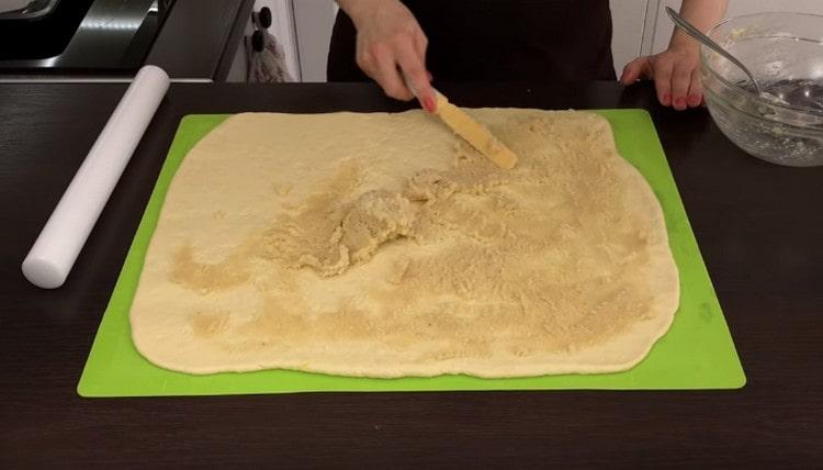 We roll out the dough into a thin large layer and grease it with a marzipan mixture.