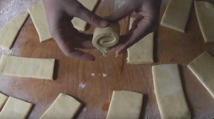 Nous tordons chaque bande de pâte avec un rouleau.