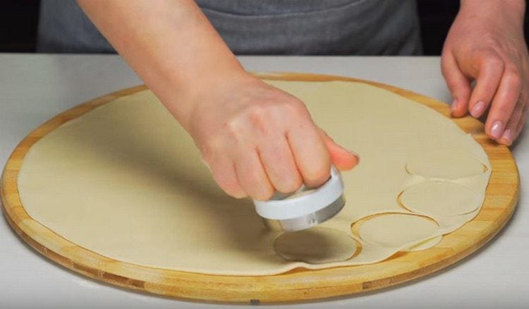 Roll out the dough and cut out circles for dumplings from it.