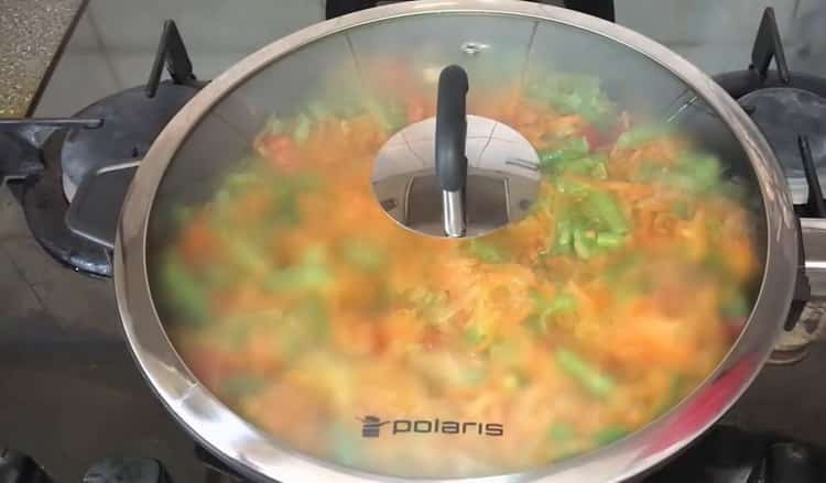 Stew vegetables under the lid to cook stuffed mackerel.