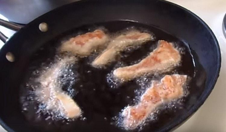 One at a time, spread the pieces of fish batter into the heated oil.