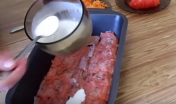 Coloque los trozos de pescado en la forma, vierta sobre la salsa de crema agria con leche.