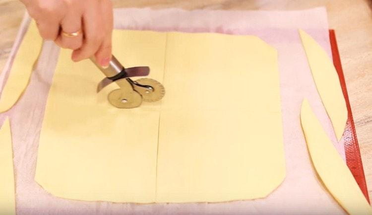 Rouler la pâte feuilletée finement. couper le calque résultant en carrés.