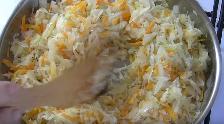 Cabbage with carrots is added to the pan to the onion.