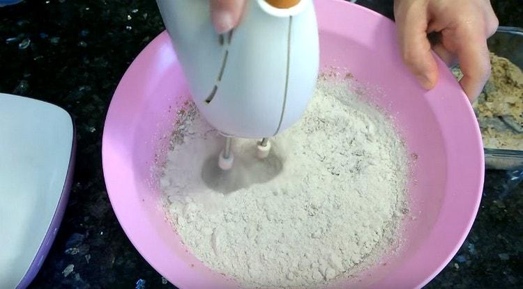 Mezclando la masa con una batidora, agregue la harina.