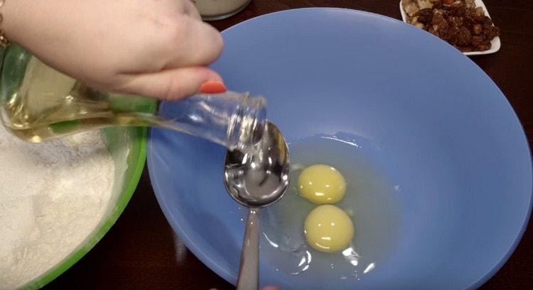 Drive two eggs into a bowl, add vegetable oil.