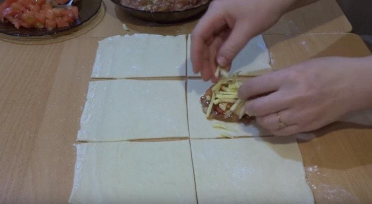Extendemos el relleno de carne en el centro del cuadrado, agregamos tomate y queso encima.