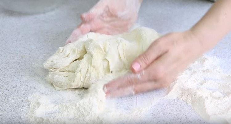 We put the soft dough on the table, roll in flour, knead.