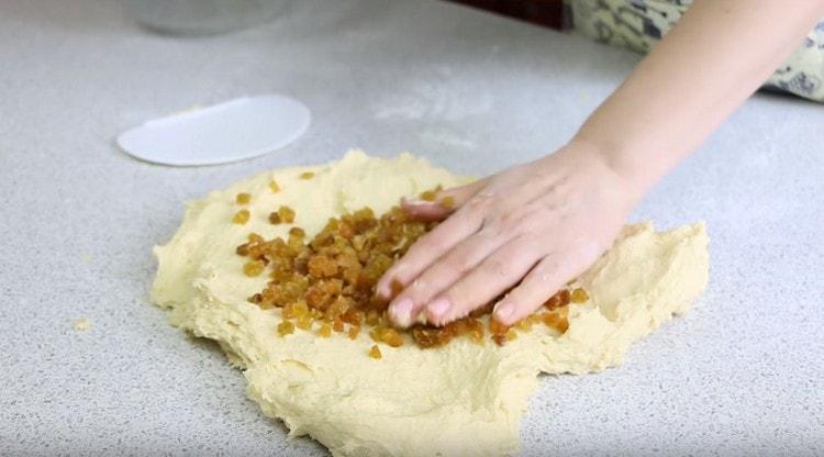 We stretch the dough and put washed and dried raisins on it.