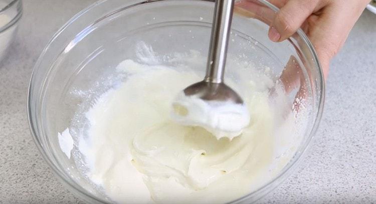 Fromage cottage avec un mélangeur à main est interrompu avec du lait jusqu'à consistance lisse.