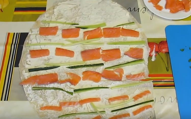 We lay out pieces of fish and cucumber on greased pita bread.