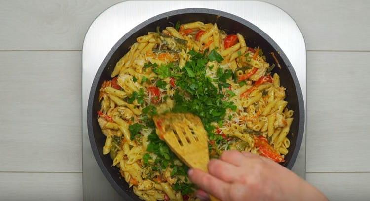 Rasporedite tjesteninu u tavi, dodajte rajčicu i sjeckano zelje.