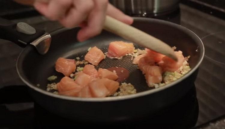 Avec l'ail haché, répartissez le saumon dans une casserole jusqu'à l'oignon.