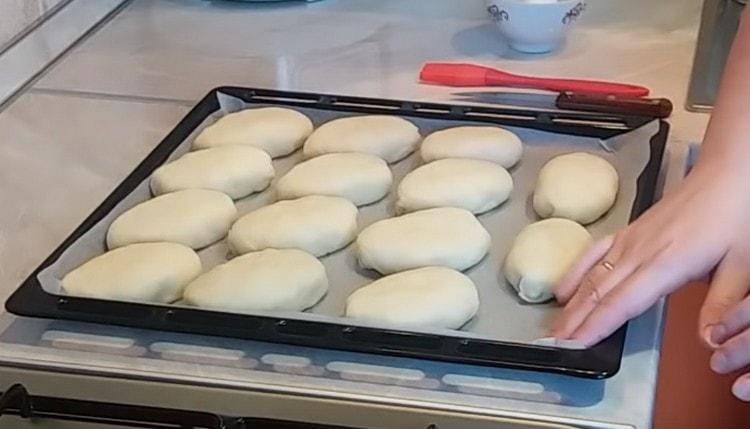 Formed pies spread on a baking sheet covered with baking paper.