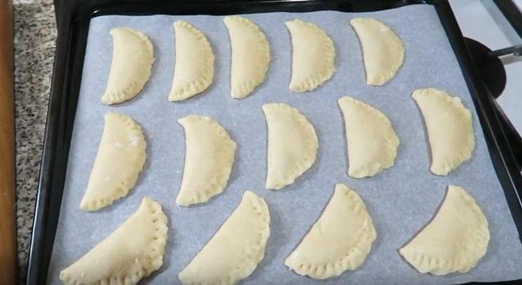 We spread the ready-made pies on a baking sheet covered with parchment and send it to the oven.