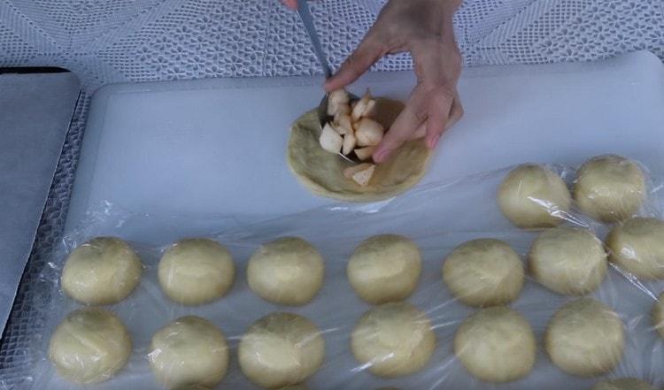 Amasar cada bola de masa con una mano en un pastel y poner relleno de manzana en su centro.