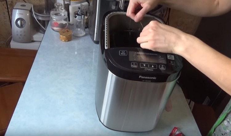 We install a bucket with components for preparing bread in a bread machine.