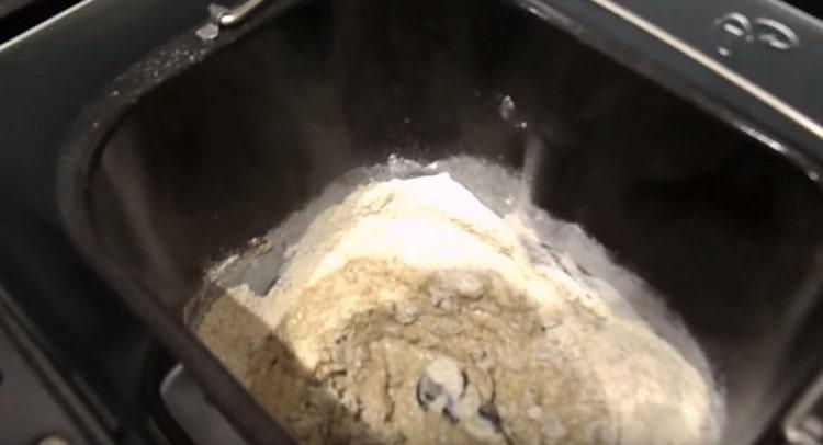Dans le seau de la machine à pain, on étale le levain, on ajoute un peu de farine de seigle et de l'eau.