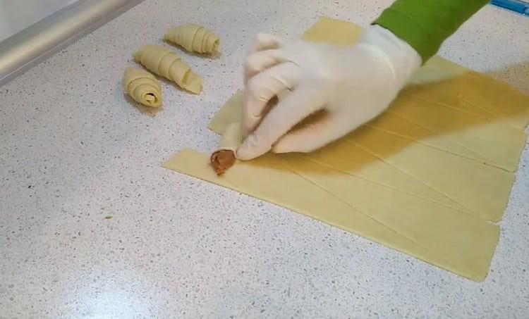 Après avoir fait une petite incision sur le bord de la pâte, nous l'enveloppons dans des directions différentes, comme si nous enveloppions le lait concentré.