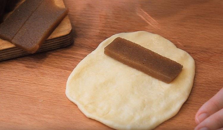 Nous alignons chaque boule de pâte sur un cercle et posons un morceau de confiture sur l’un de ses bords.