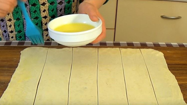 Grease each strip of dough with melted butter.