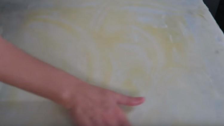 Lubrifiez la couche de pâte obtenue avec du beurre fondu dans de l'eau chaude.