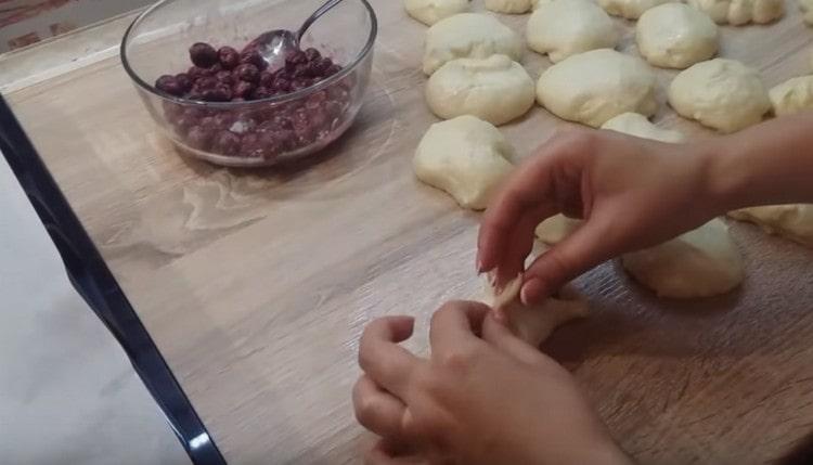 Pétrir chaque morceau de pâte dans un gâteau, y déposer les cerises, puis pincer les bords.