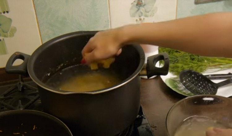 Nous répandons les pommes de terre dans le bouillon fraîchement bouilli.