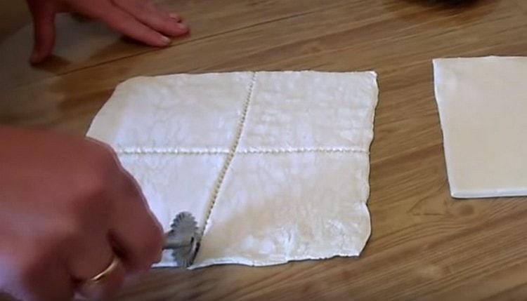 Abaisser un peu la pâte et la couper en carrés.