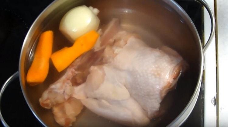 Extendemos la carne de pollo, la cebolla y la zanahoria en una sartén, vierte agua.