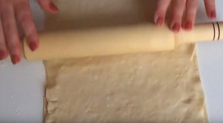 Cover the filling with a second piece of dough and roll out the workpiece with a rolling pin.