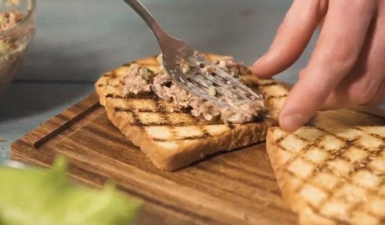 Spread a mass of tuna on toasted bread.