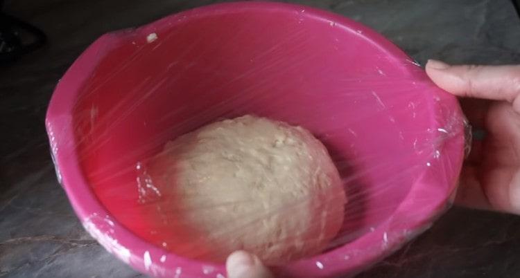 We cover the dough with cling film and leave it in a warm place so that it rises.