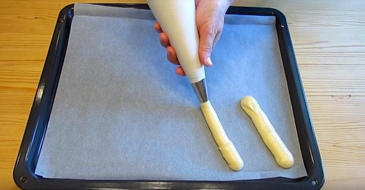 À l'aide d'une poche à pâtisserie, nous plantons les éclairs sur un parchemin recouvert de parchemin.