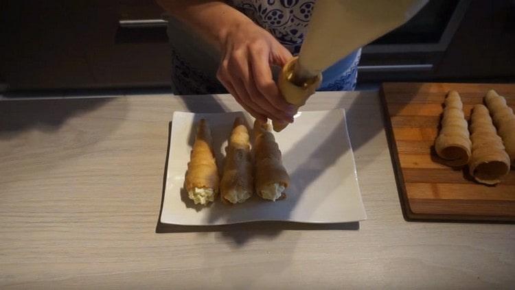 Using a pastry bag, fill the tubes with cream.