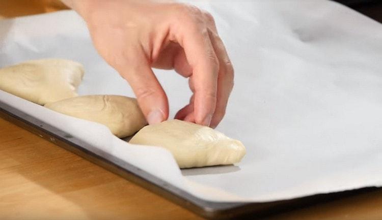 En la bandeja para hornear cubierta con pergamino, coloque el samsa con la costura hacia abajo.