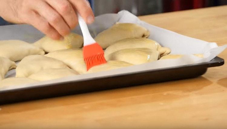 Directamente en la bandeja para hornear, engrase samsa con una mezcla de yema de huevo y leche.