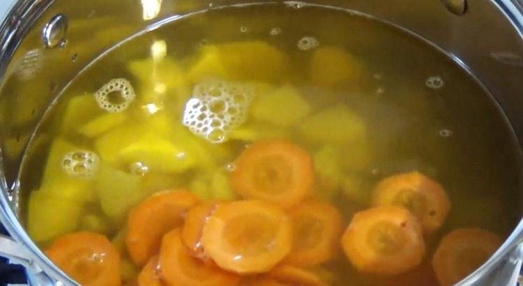 Add potatoes and sliced ​​carrots to the boiling broth.