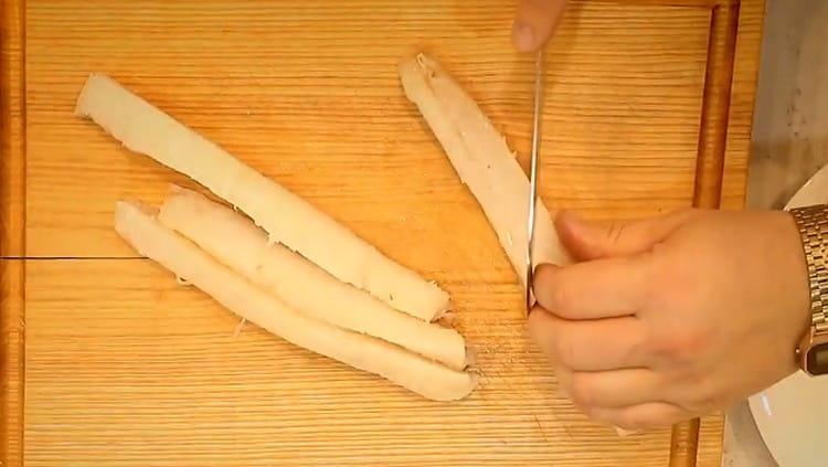 Kabeljauwfilet in lange reepjes gesneden, die elk schuin in tweeën worden gesneden.
