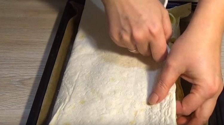 Recouvrez la garniture de morceaux de pain pita humidifié, puis couvrez toute la structure avec le bord libre du pain pita.