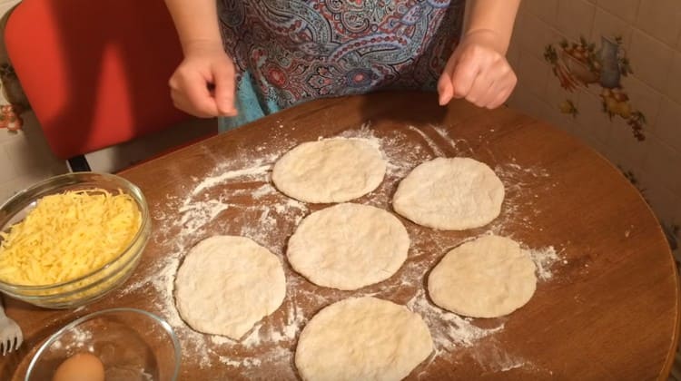 Pinapalabas namin ang bawat piraso ng kuwarta o masahin ito sa isang flat cake gamit ang aming mga kamay.