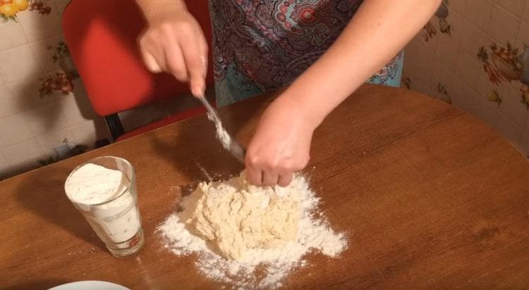 Pour the remaining flour onto the table and transfer the dough into it.