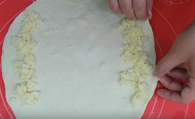 Nous roulons chaque partie de la pâte en un cercle, étalons le remplissage sur les bords.