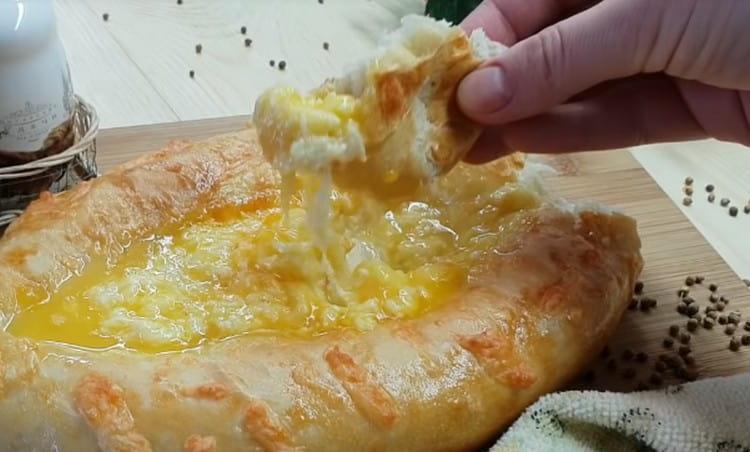 Khachapuri in Adjarian style is eaten, mixing the filling with the egg and dipping pieces of dough into it.