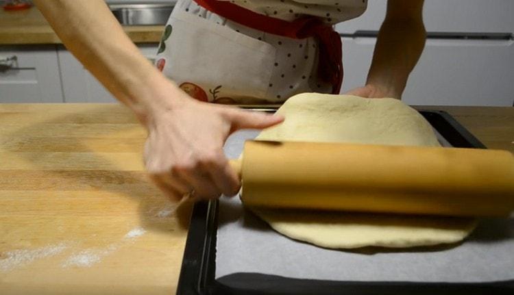 Usando un rodillo, transfiere el khachapuri a una bandeja para hornear.