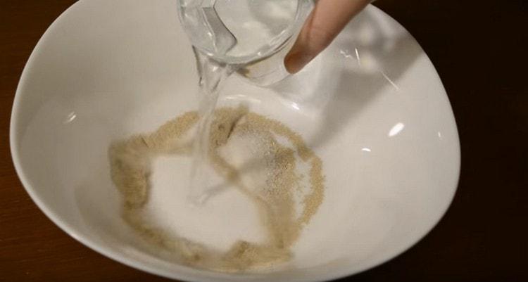 En un tazón, mezcle la levadura, el azúcar, agregue agua.