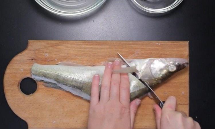 Without cutting to the end, we separate the head of the fish from the body.