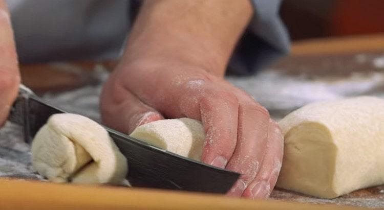 Ρίχνουμε κάθε κομμάτι ζύμης σε λουκάνικο και το κόβουμε σε μερίδες.